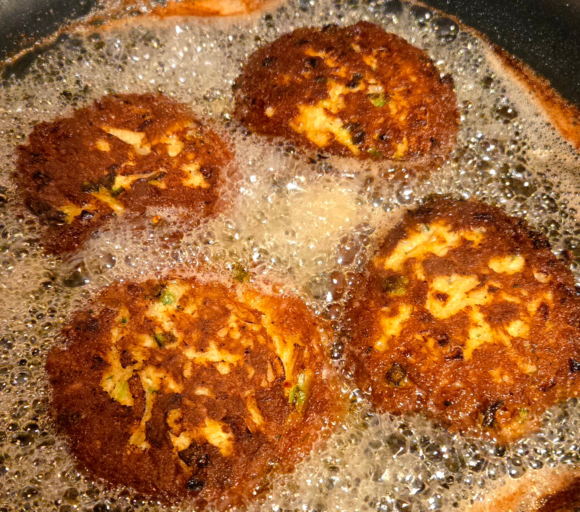 Seared crab cakes frying in butter